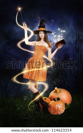 Pretty young woman as halloween witch with magic wand, magic book and pumpkin\'s