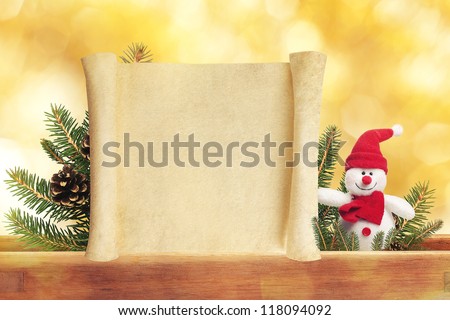 Cute toy snowman on golden background with blank scroll