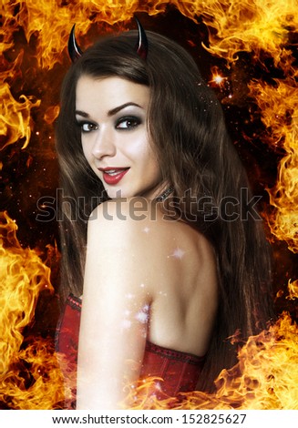 Beautiful young brunette woman as sexy devil in fire