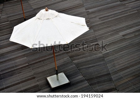 big white umbrella with wooden stick and metal plate standing on wooden floor