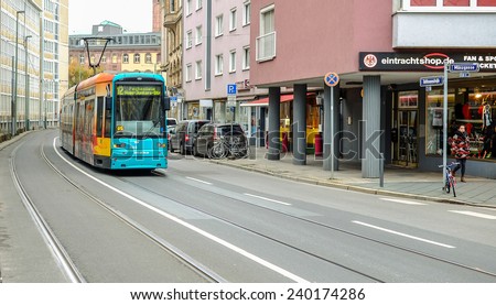 FRANKFURT, GERMANY -November 27, 2014: photo of green tram traveling in Frankfurt with an unidentified people walking nearby in cloudy day on November 27, 2014 close to Saint Bartholomew\'s Cathedral