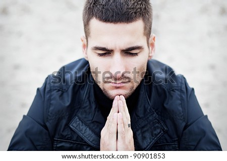 Praying white man in dark clothing on a light background