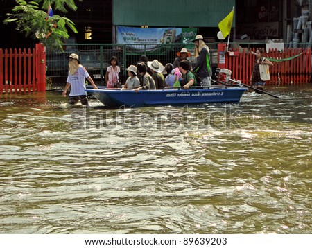 LAMLUKKA (PATHUMTHANI), THAILAND – CIRCA NOVEMBER 2011 Several unidentified people on a boat sail through a flooded road circa November 2011 in Lamlukka.