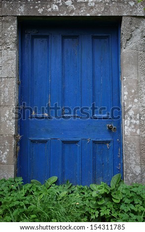 Old, wooden blue door framed with old stone