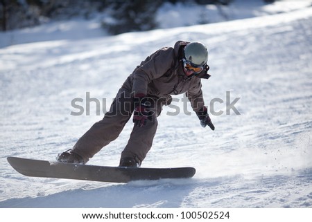 Man snowboarding down the slope going to stop