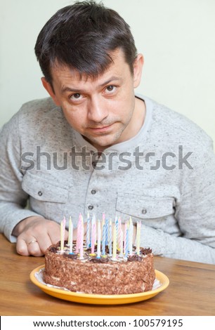 Man at birthday cake looking at camera
