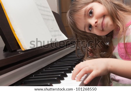 Little girl smiling at piano keyboard