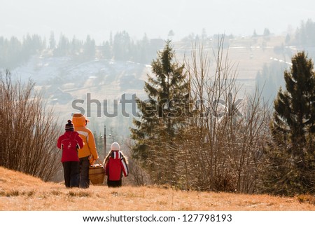 Family go for picnic with basket in the winter mountains. Back view
