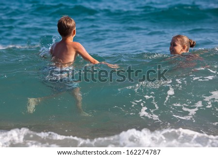 Happy child swimming in a waves in the sea