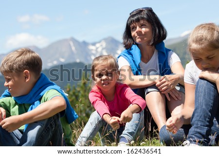 Portrait of a mother with three children outdoors the summer with snow covered mountains in the background