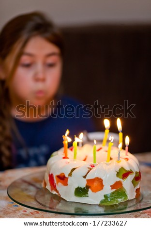 Colorful candles on birthday jelly cake in the dark. Focus on cake