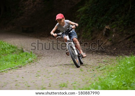 9 old boy riding his bike in park at speed. Blurred motion. Front view