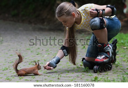 Cute little girl with roller blade feeding squirrel at park