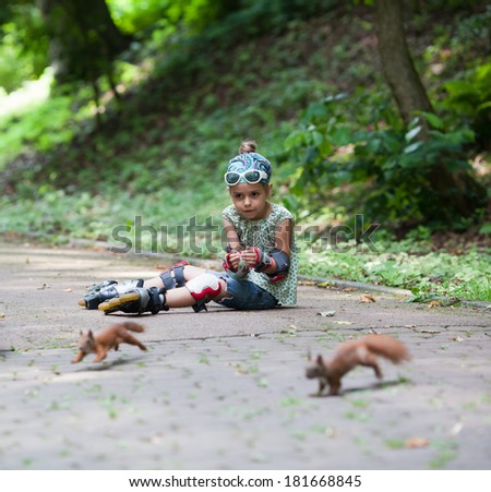 Cute little girl with roller blade and squirrels at park
