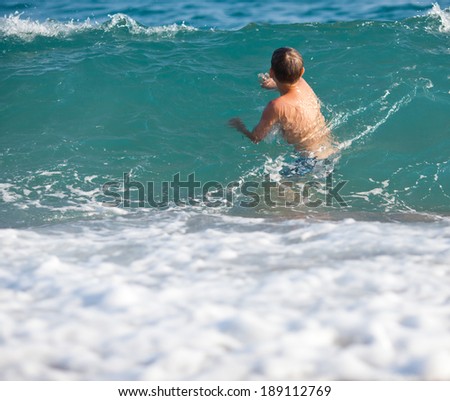 Little boy swimming in a waves in the sea