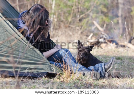 Woman with a dog resting at camp in the forest