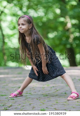 Six year old funny little girl dancing in park