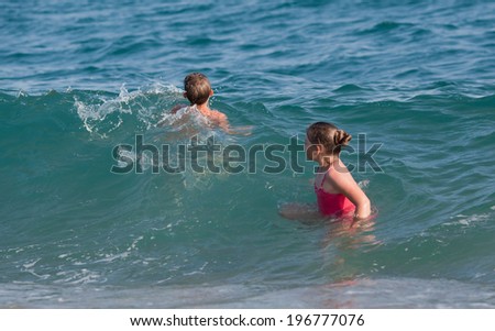 Happy child swimming in a waves in the sea