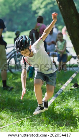 Little boy balancing on a tightrope on the background of people in the park