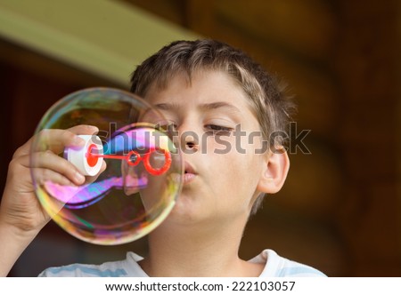 Boy blowing the big soap bubble outdoors. Close up