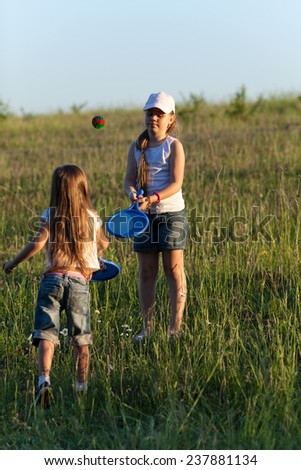 Two sisters playing tennis on the lawn in evening light
