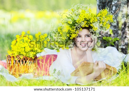 the beautiful young girl in flowers smiles outdoors