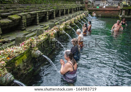 TAMPAK SIRING, BALI, INDONESIA - 26 JULY 2013: People praying at holy spring water temple Puru Tirtha Empul during the religious ceremony on July 26, 2013 in Tampak Siring, Bali, Indonesia