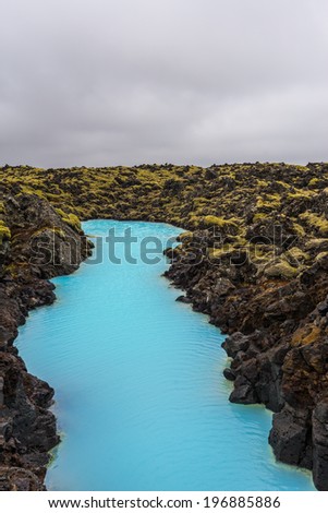 The blue water between the lava stones covered with moss just outside the Blue Lagoon resort of Iceland