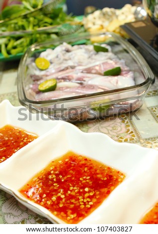 Asian dishes - spicy dipping sauce for steamboat and fresh squids set in shallow depth of field