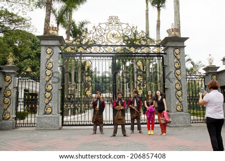 KUALA LUMPUR, MALAYSIA - FEBRUARY 17: Tourists taking photo with armed guards in traditional Malay costume at the entry gate of Royal Museum in Kuala Lumpur, Malaysia on February 17, 2013