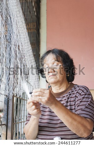 SARAWAK, MALAYSIA - SEPTEMBER 23: Unidentified Bidayuh woman mending her fishing net in Sarawak, Malaysia on September 23, 2010. Bidayuh is one of the indigenous tribes of Borneo Island