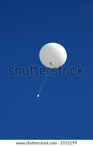 A white weather balloon is ascending into the blue sky. Picture was taken during a 3-month Antarctic research expedition.