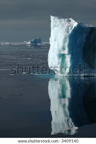 Bright sunlit side of an Antarctic iceberg. Icebergs and snow petrels in the background.
