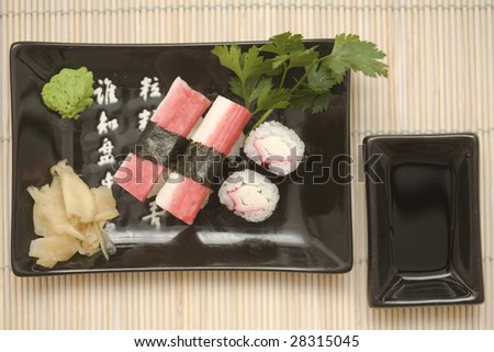 A set of sushi on a black plate with wasabi and gari, on a makisu (bamboo rolling mat).