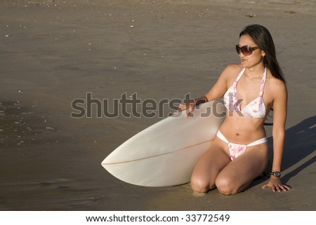 An asian surfer woman, in her 20\'s on the beach wearing a bikini.