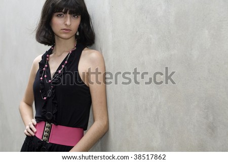 An 18 year old exotic brazilian model, with short dark hair, a young looking face and a skinny body. She is wearing a black dress and pink belt. Plenty of copyspace in the image.