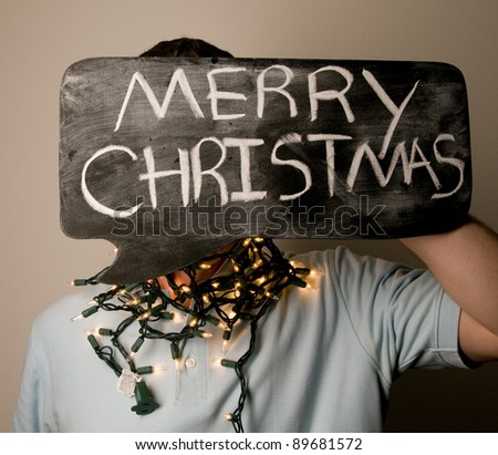 Man Holding Merry Christmas Sign with Christmas Lights.