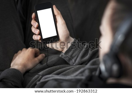 Man listening to the music and holding smart phone with blank screen Man listening to the music and holding smart phone with blank screen