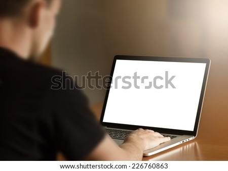 Man using notebook with blank screen in living room. third person view.
