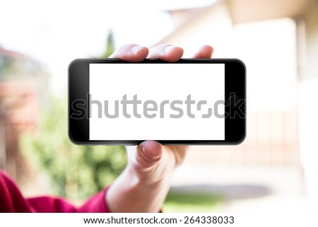 Man\'s hand shows mobile smartphone in horizontal position, blurred background - mockup template