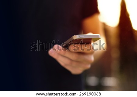 Man using mobile smartphone - focus on top of the phone