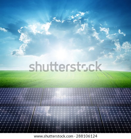 Photovoltaic ecological modules on green grass valley against of sun behind cloudy sky
