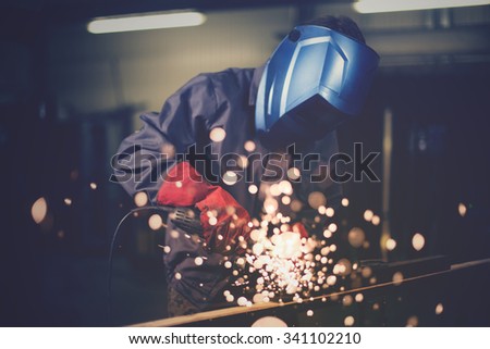 Employee grinding steel with sparks - focus on grinder.