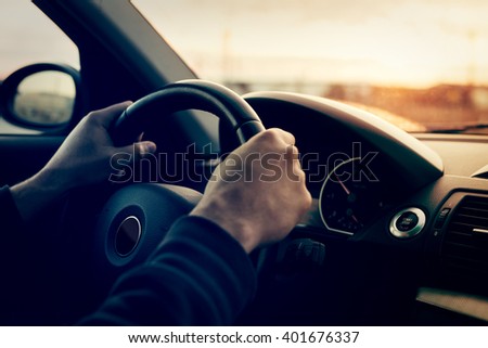Driving a car at sunset - focus on steering weel