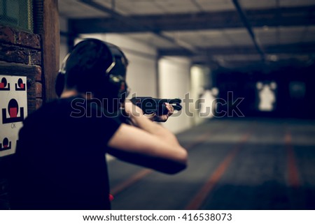Man aiming shotgun at target in indoor firing range or shooting range