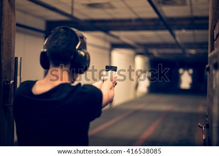 Man aiming pistol at target in indoor firing range or shooting range