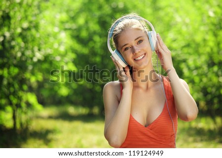 Young woman with headphones on green grass in the park