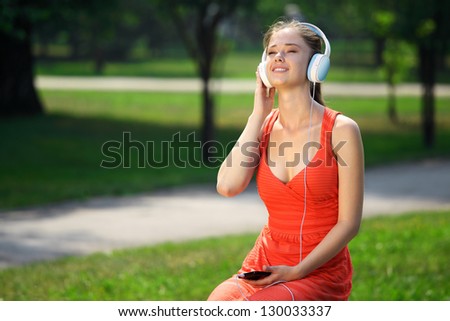 Young woman with headphones on green grass in the park