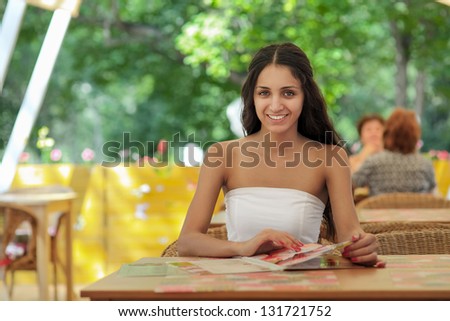 Young girl sitting on the porch in the restaurant and choose fro