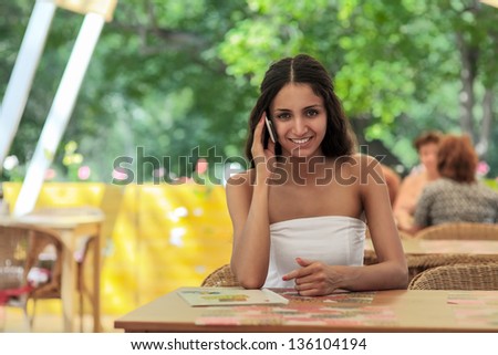 Young girl sitting on the porch in the restaurant and calling on